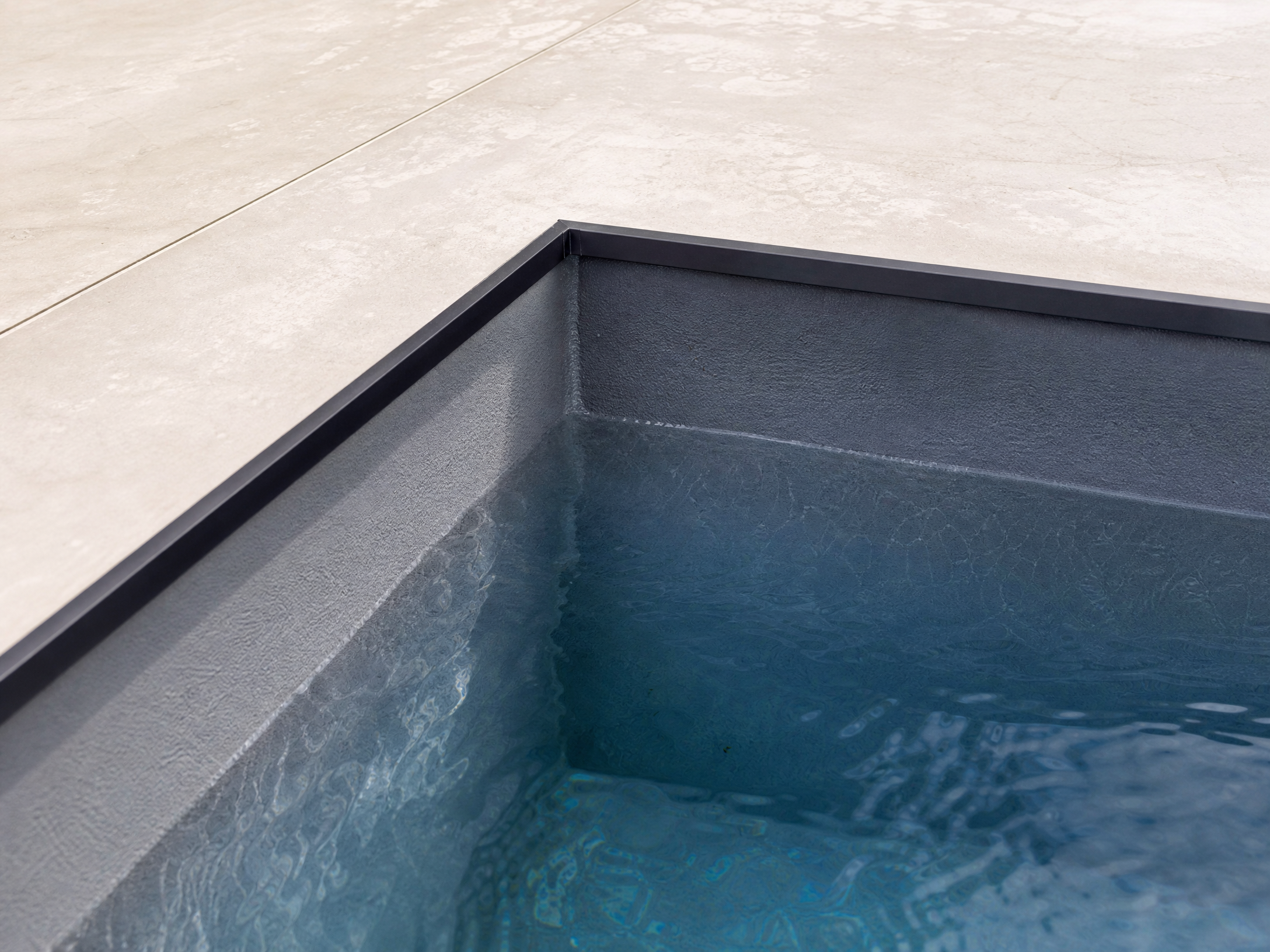 Detail der dunklen Poolkante und Wasseroberfläche